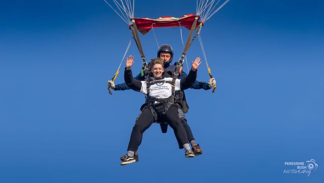 Kai holding onto parachute mid-air