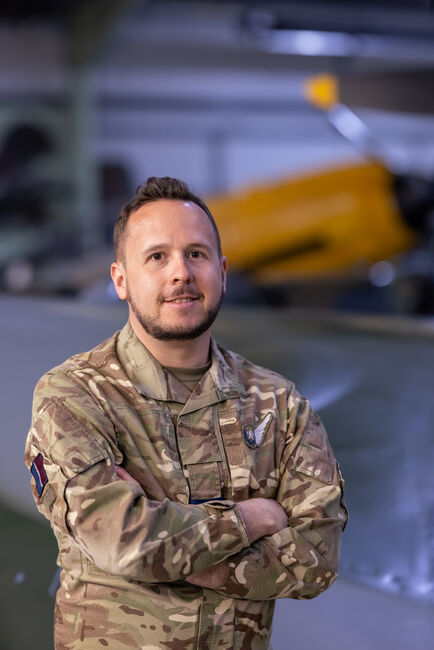 A posed image of Neil Robinson in uniform inside of a RAF hangar