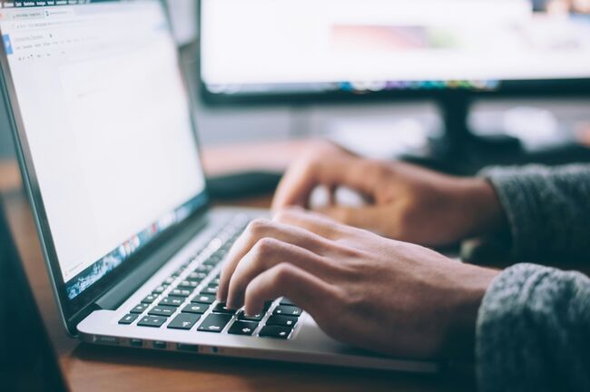 Close up image of a pair of hands typing at a laptop 